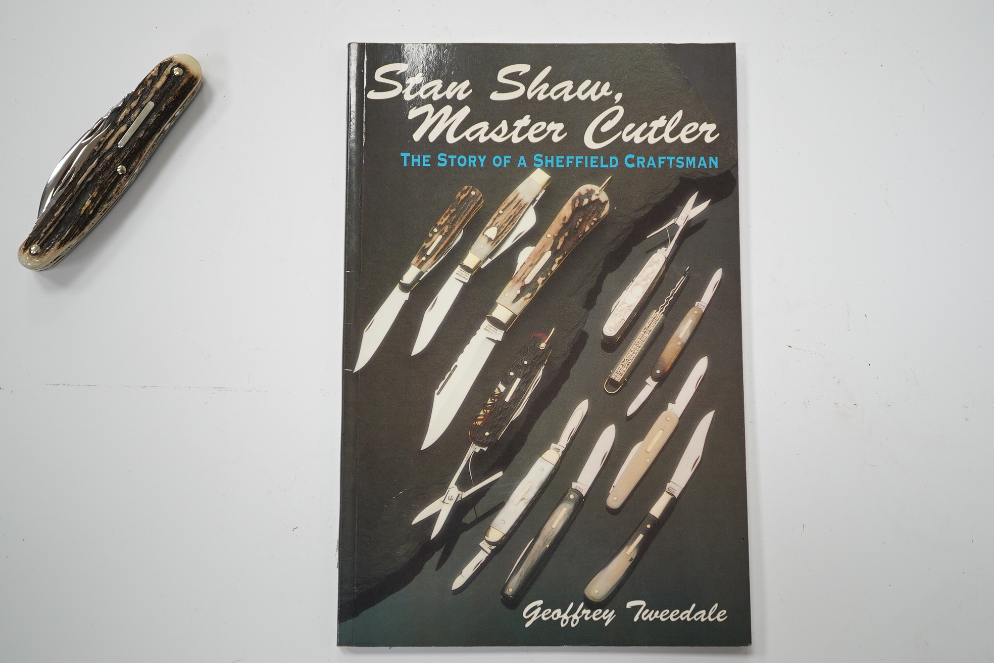 Stan Shaw, two knives; a pen knife with horn handle and a folding knife and a related book, signed. Condition - good